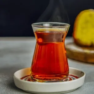 A traditional Turkish tea glass filled with aromatic Turkish tea, served on a decorative saucer.