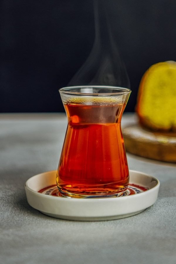 A traditional Turkish tea glass filled with aromatic Turkish tea, served on a decorative saucer.